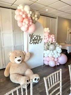 a teddy bear sitting on top of a chair next to balloons