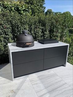 a bbq grill sitting on top of a table next to bushes