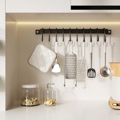 a kitchen with white counters and utensils hanging on the wall above it,