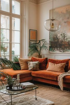 a living room filled with lots of furniture and plants on top of a wooden floor