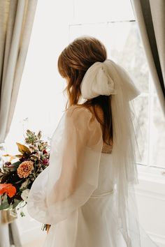 a woman standing in front of a window wearing a veil