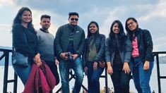 a group of people standing next to each other in front of a body of water