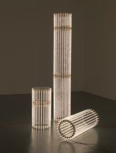 three tall glass tubes sitting next to each other on top of a black floor covered in lights