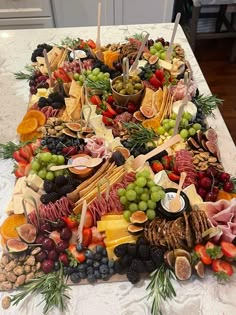 a table topped with lots of different types of cheeses and fruit on top of it