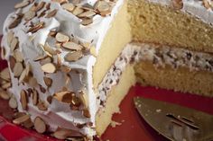 a slice of cake with white frosting and almonds on top is sitting on a red plate