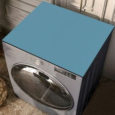 a blue and silver washer sitting on top of a floor next to a basket