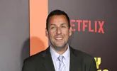 a man in a suit and tie standing next to a wall with the netflix logo on it