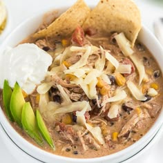 a white bowl filled with soup and tortilla chips on top of a table