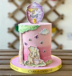 a pink and yellow cake with an image of a bear holding a balloon on top