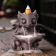 a small dragon fountain is sitting on a piece of wood with water coming out of it