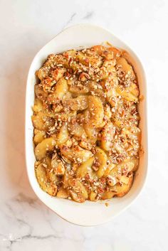 a casserole dish filled with bananas and nuts on a marble countertop, ready to be eaten