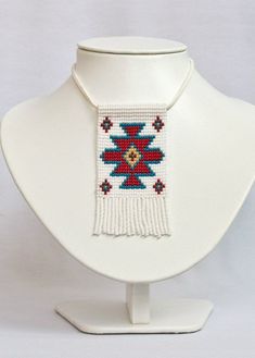 a white mannequin with a red and blue beaded necklace on it