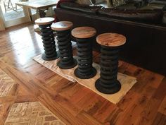 four stools sitting on top of a wooden floor in front of a black couch