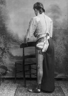 an old photo of a woman standing in front of a chair with her back to the camera