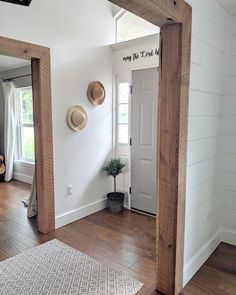 an entry way with white walls and wood floors, two hats hanging on the wall