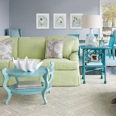 a living room filled with blue and green furniture next to a white table in front of a window