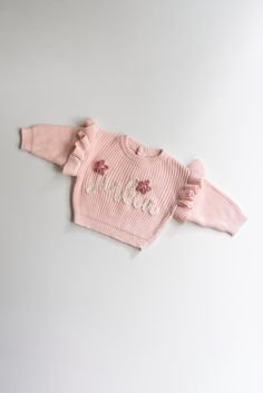 Personalized hand embroidered knits and more! Great for newborn or family photos, birthday photos, gifts (birthday, baby shower, Christmas, Easter Baskets, etc.), gender reveals, birth announcements, and many other occasions or just because! Reach out with any questions or design ideas! These one-of-a-kind, custom, hand-stitched sweaters make the perfect gifts. Choose a name, nickname, phrase, letter, or age. Cutest birth announcement, name reveal, or Christmas gift. Check us out on Instagram for more photos and inspiration @baebandbuddy Please note:  - actual sweater romper and yarn colors may appear slightly different from photos  - sweater are not handmade  - How to care: hand wash, cold. Hang or lay flat to dry Stitching:  - Stitching is hand embroidered and will vary. Size of letters Ruffle Sweater, Flower Letters, Embroidered Sweater, Pink Ruffle, Sweater Making, Birthday Photos, Gender Neutral Baby, Yarn Colors, Baby Announcement