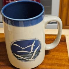 a blue and white coffee mug sitting on top of a wooden table