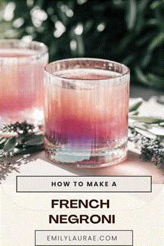 two glasses filled with pink and purple liquid sitting on top of a table next to greenery