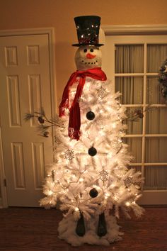 a white christmas tree with a snowman on top