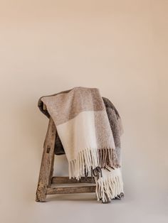 a blanket sitting on top of a wooden step stool next to a white and brown wall