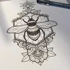 a drawing of a bee on top of a piece of paper with a pen next to it