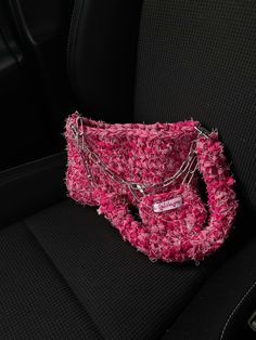 a pink purse sitting in the back seat of a car with chains attached to it