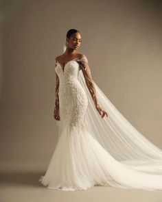 a woman in a white wedding dress with long veil on her head and hands behind her back