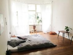 a bed sitting on top of a wooden floor next to a window