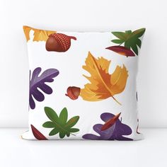 a pillow with colorful leaves and acorns on it, against a white background