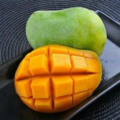 two pieces of mango sitting on top of a black plate