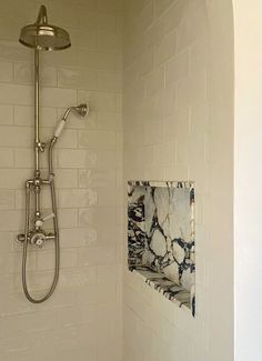 a bathroom with a shower head, toilet and tiled walls in it's corner