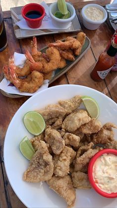 there is a plate of fried shrimp and dipping sauces on the table next to it