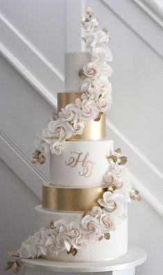 a white and gold wedding cake with flowers on it