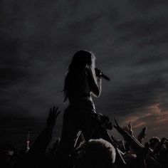 a woman standing on top of a stage with her hands up in the air while singing