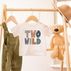 a teddy bear and two t - shirts hanging on a clothes rack