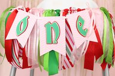 a number banner is hanging from a chair with ribbons around it and the numbers are decorated in green, red, and pink