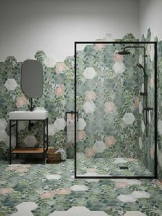 a bathroom with green and pink wallpaper, white sink, mirror and stand up shower