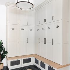 a kitchen with white cabinets and black tile flooring in the center, along with a potted plant