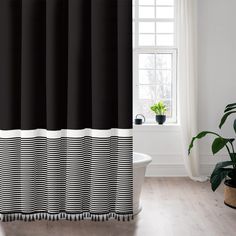 a black and white striped shower curtain next to a bathtub with potted plants