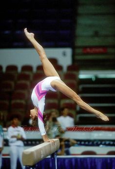 a woman on a balance beam doing a handstand