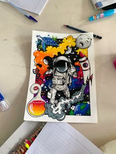 a drawing of an astronaut floating in space surrounded by colored pencils and crayons