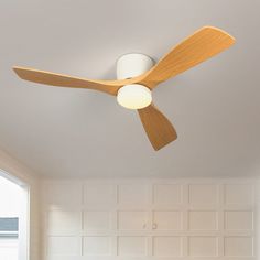 a ceiling fan with two light bulbs on it in a room that has white walls and wood paneling