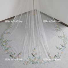 a bed with a white canopy over it and flowers on the ground underneath it in a room