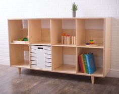 a book shelf with books and other items on it in front of a white brick wall