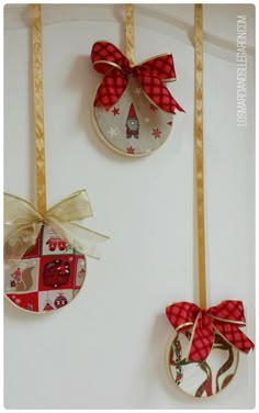 three ornaments are hanging on the wall with bows and ribbons attached to each ornament