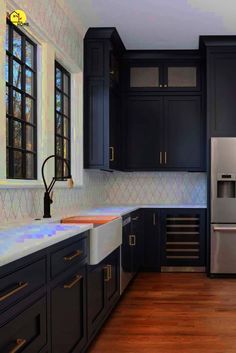 a kitchen with black cabinets and stainless steel appliances in the center, along with wood flooring