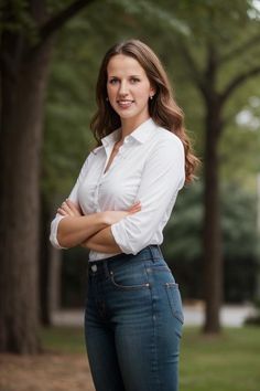 a woman standing in front of trees with her arms crossed