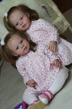 two dolls are laying on the floor next to each other and one is holding another doll