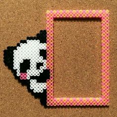 a beaded picture frame with a black and white cat in the middle on a cork board